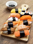 A couple rolls sushi side-by-side in an interactive sushi-making experience, ideal for date nights in London.
