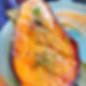 Grilled eggplant on a blue plate, topped with sesame seeds and chives. A golden sauce is spread beside it, creating a savory mood.